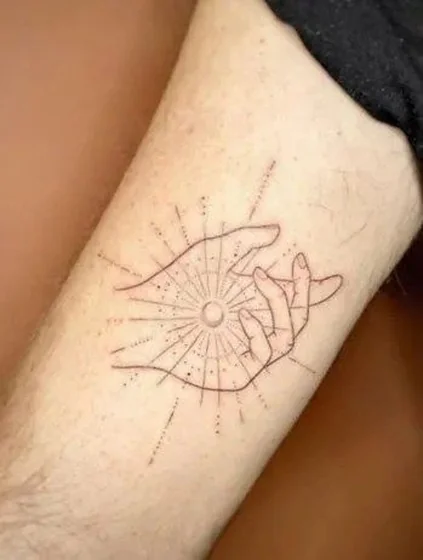 Minimalist fine line sun and hand tattoo idea for men on upper arm