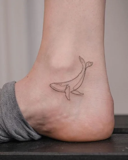 Minimalist fine line whale tattoo design for men and women on ankle