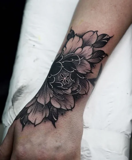Neo-Traditional black and grey floral tattoo design for women on hand and wrist