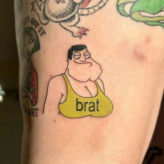 New School patchwork cartoon character 'Brat' tattoo idea on upper arm.