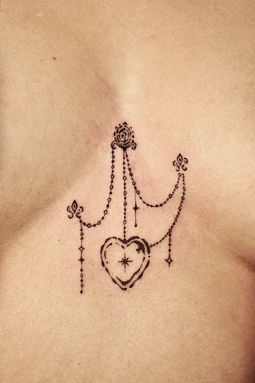 Ornamental Fine Line heart and chain tattoo idea for women.