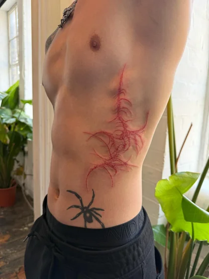 Patchwork abstract spider and vein tattoo idea for men with scarification aesthetic on rib and hip tattoo ideas