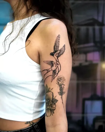 Patchwork fine line bird, floral tattoo on arm for women.