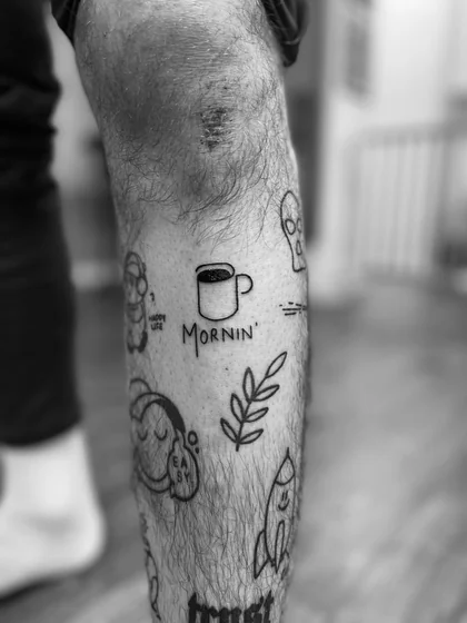 Patchwork fine line tattoo design for men: coffee cup, rocket, alien, vine on leg.