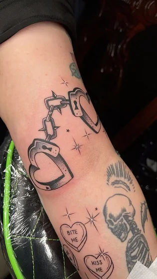 Patchwork heart handcuffs tattoo for women on upper arm.
