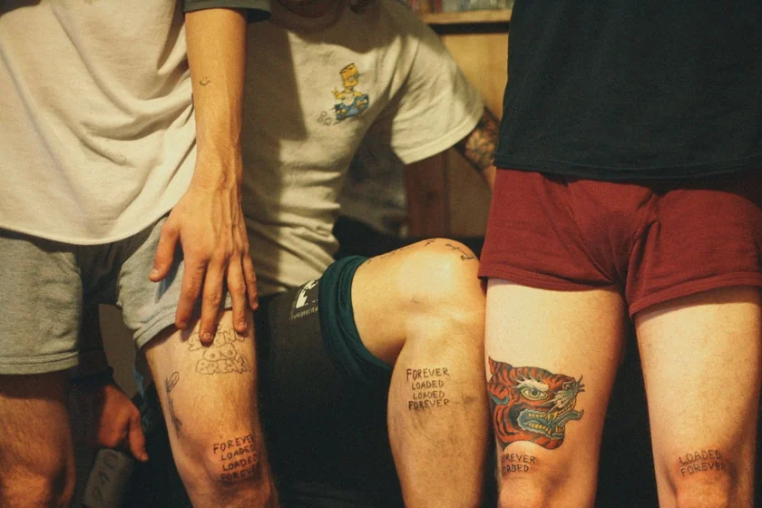 Patchwork tiger, quote, and smiley face tattoo ideas for men on thigh and forearm