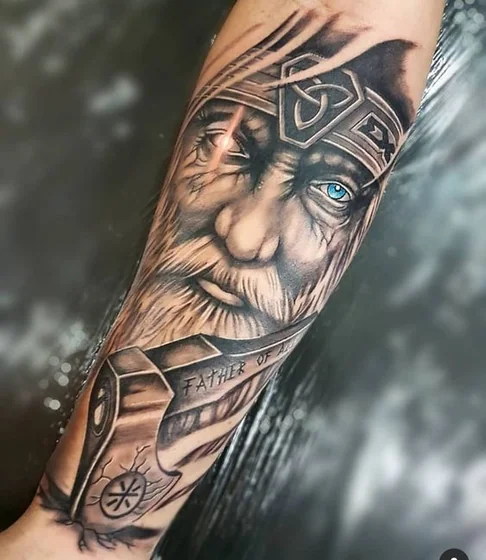 Realistic Viking god with axe tattoo idea for men on forearm.