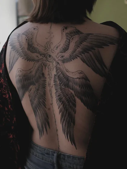 Realistic black and grey angelic wings with eyes tattoo design for women on back