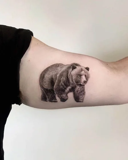 Realistic black and grey bear tattoo idea for men on upper arm