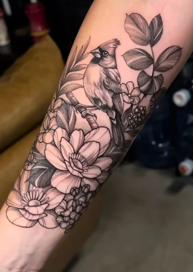 Realistic black and grey bird and floral tattoo design for women on forearm