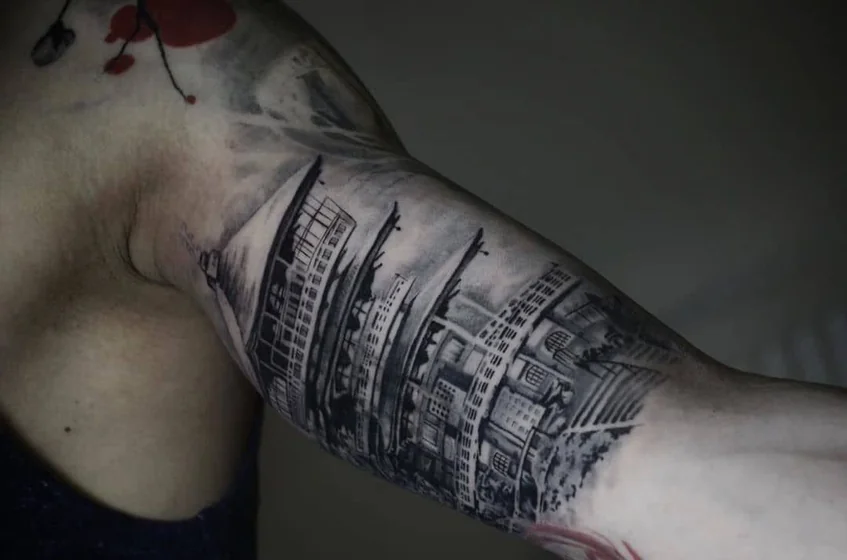 Realistic black and grey cityscape tattoo design for men on upper arm