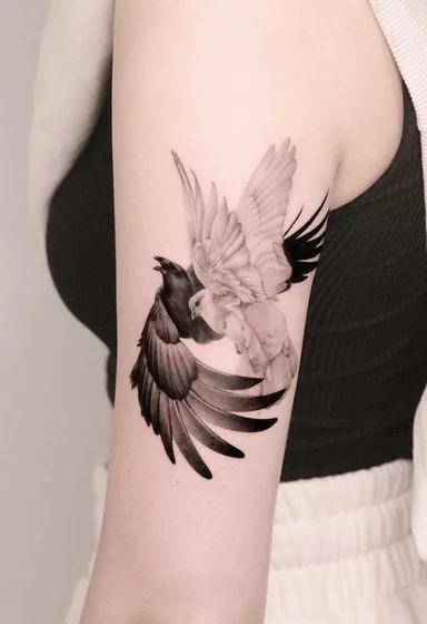 Realistic black and grey dove and raven wing tattoo design for women on upper arm