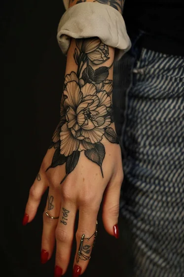 Realistic black and grey floral tattoo design for women on hand and wrist
