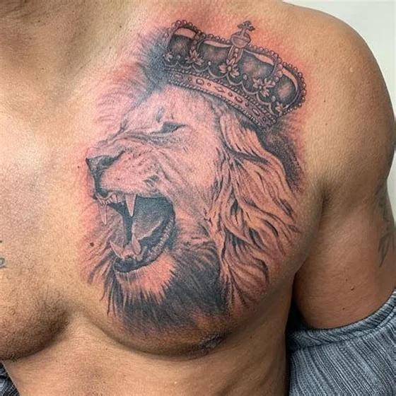 Realistic black and grey lion and crown tattoo for men on chest.