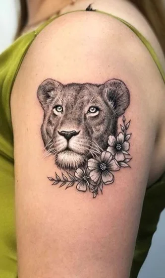 Realistic black and grey lion and floral tattoo design for women on shoulder