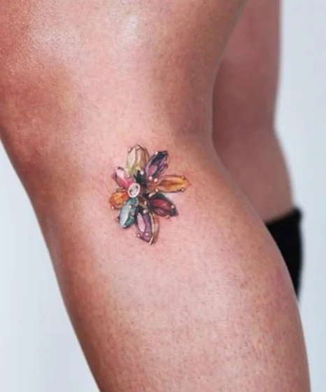 Realistic gemstone floral tattoo design for women on knee
