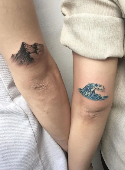 Realistic mountain and ocean wave tattoo idea for women on elbow