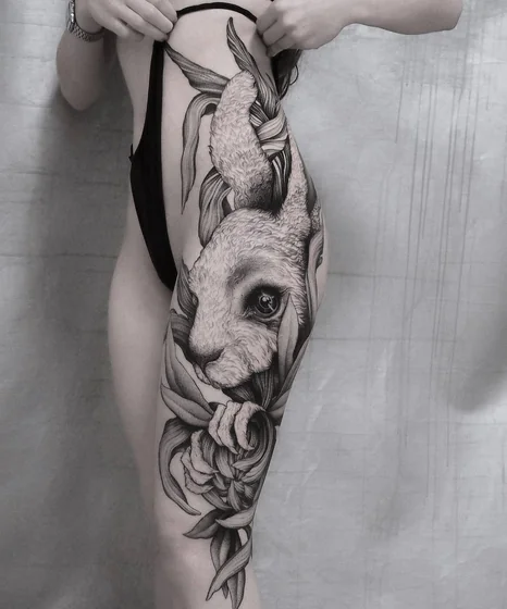 Realistic rabbit and floral black and grey tattoo design for women on thigh