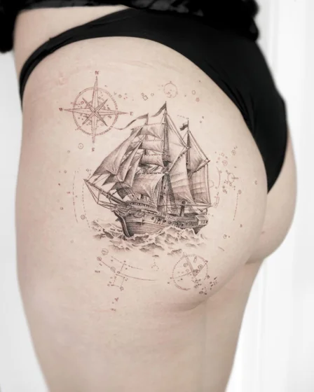 Realistic sailing ship and compass tattoo design for women on thigh