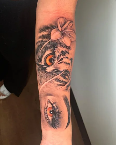 Realistic tiger and human eye with flower tattoo design for women on forearm