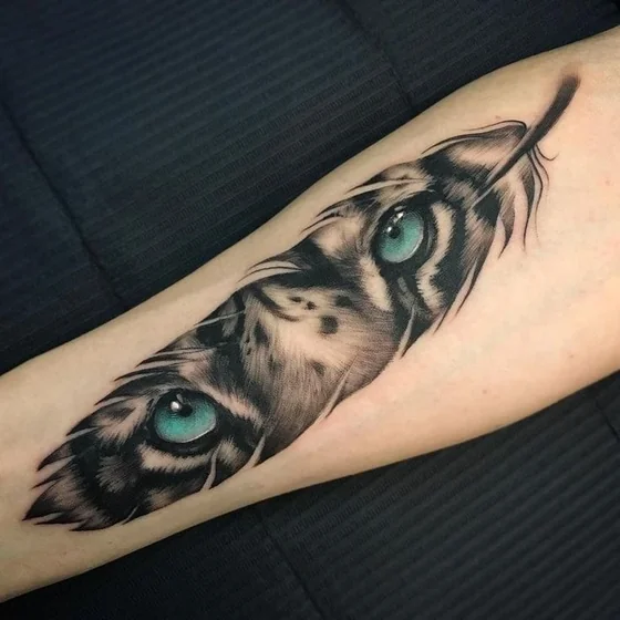 Realistic tiger eyes and feather tattoo design on forearm