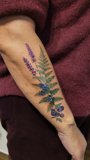 Realistic watercolor flower, blueberry, and fern tattoo design for women on forearm