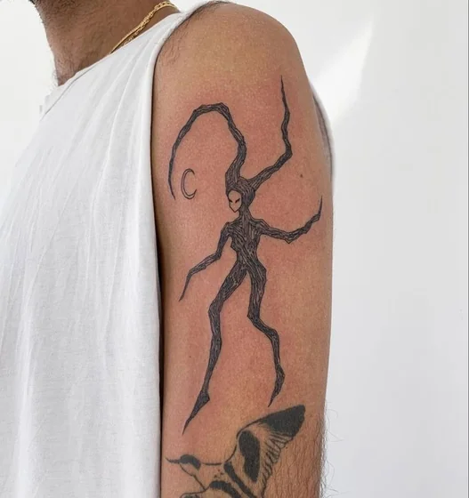 Sketchy ignorant abstract figure and moon tattoo idea for men on upper arm