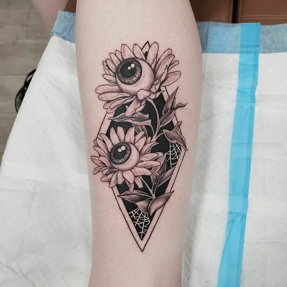 Surreal black and grey eyeball flower tattoo design for women on calf