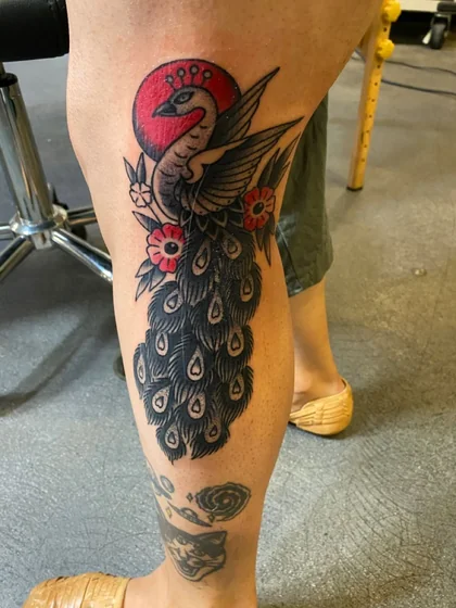 Traditional patchwork peacock and floral tattoo design for women on knee and calf