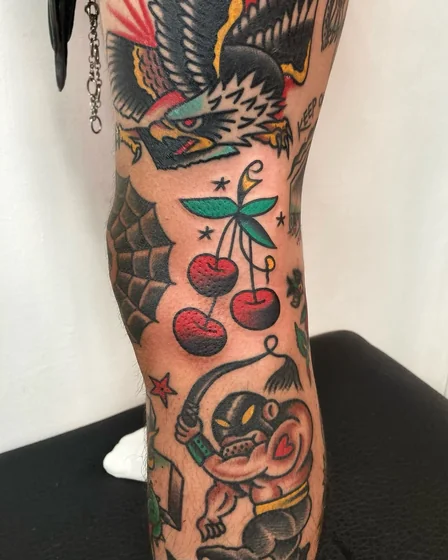 Traditional patchwork tattoo idea for men with eagle, cherries, imp on leg