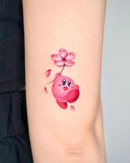 Watercolor Kirby with flower tattoo design for women on upper arm.