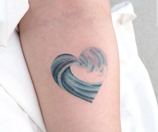 Watercolor heart and ocean tattoo design for women on upper arm