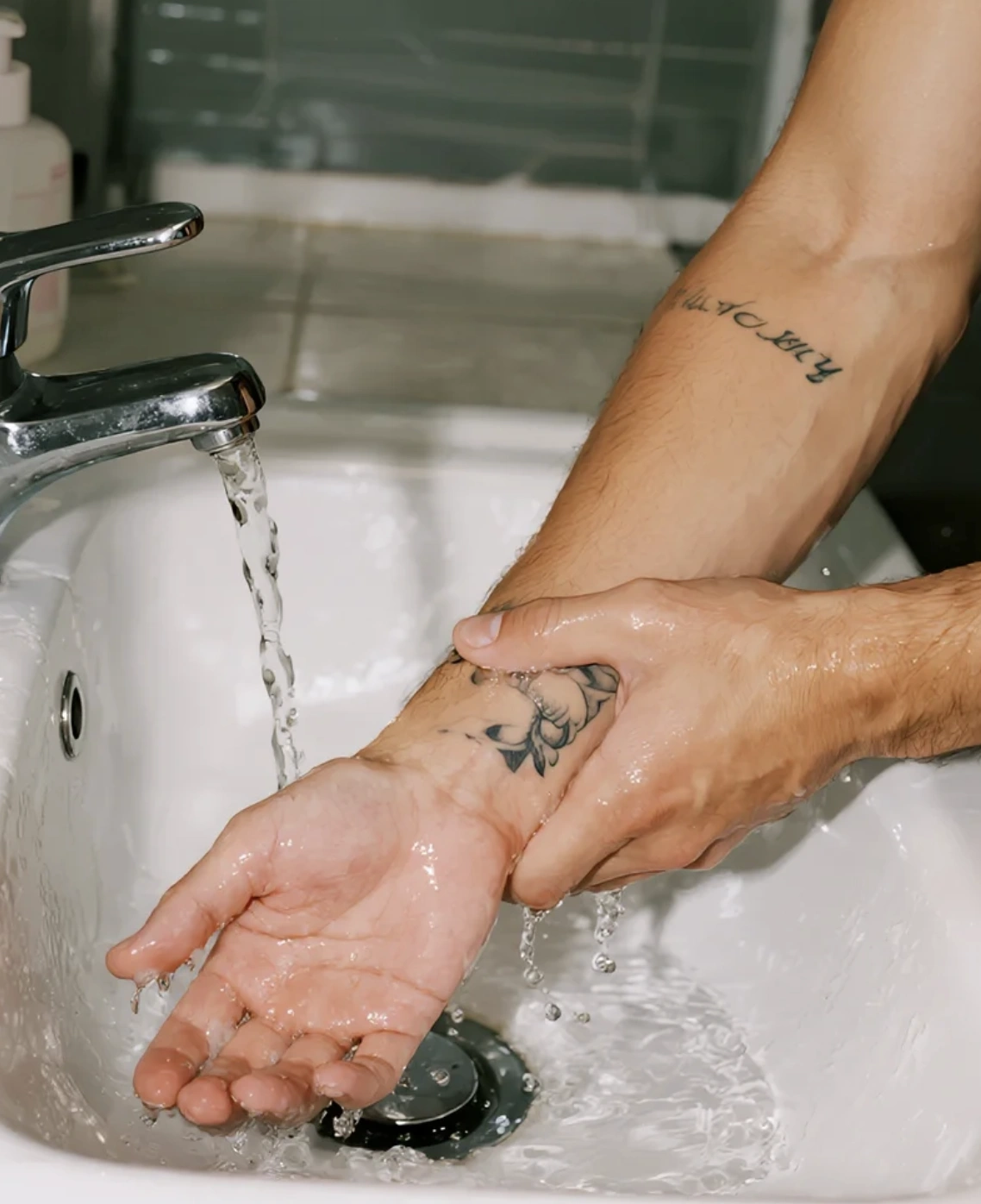 tattoo cleaning – man washing new tattoo with mild soap